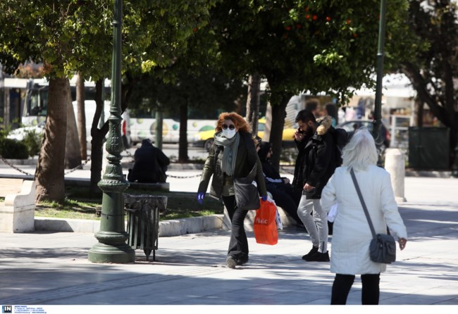 Άνθρωποι περπατούν φορώντας μάσκες