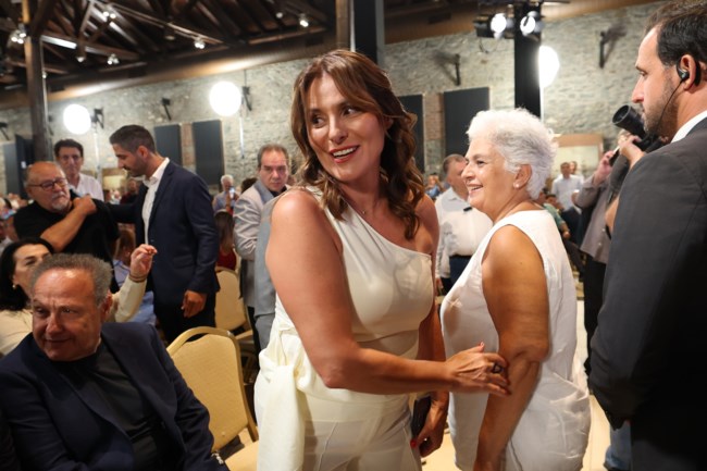 Η Μπέτυ Μπαζιάνα στα λευκά με one-shoulder σύνολο, στο πλευρό του Τσίπρα στη Θεσσαλονίκη