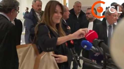Κάρλα Μπρούνι: Το ειρωνικό χαμόγελο μετά την καταδίκη Σαρκοζί - &quot;Αρπάζει&quot; επιδεικτικά τηλεοπτικό μικρόφωνο [βίντεο]