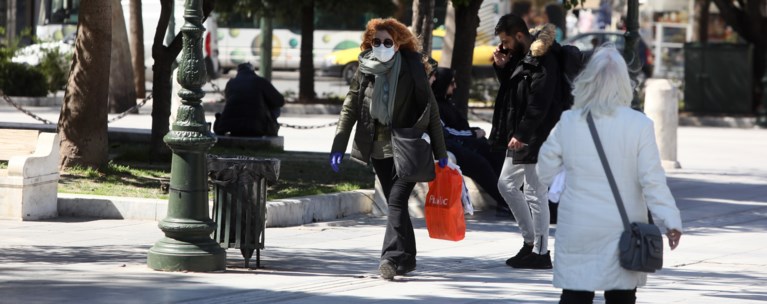 Άνθρωποι περπατούν φορώντας μάσκες