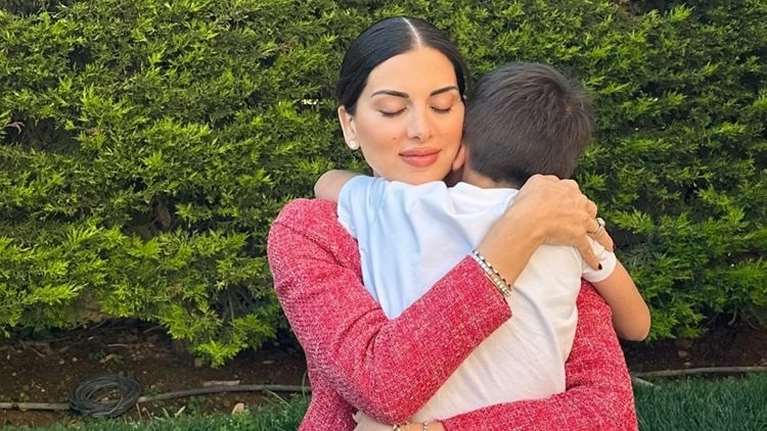 Κλασική Ελληνίδα μαμά: Η Σταματίνα Τσιμτσιλή κρατά αγκαλιά τον γιο της, που κοιτάται σε γαμήλια δεξίωση