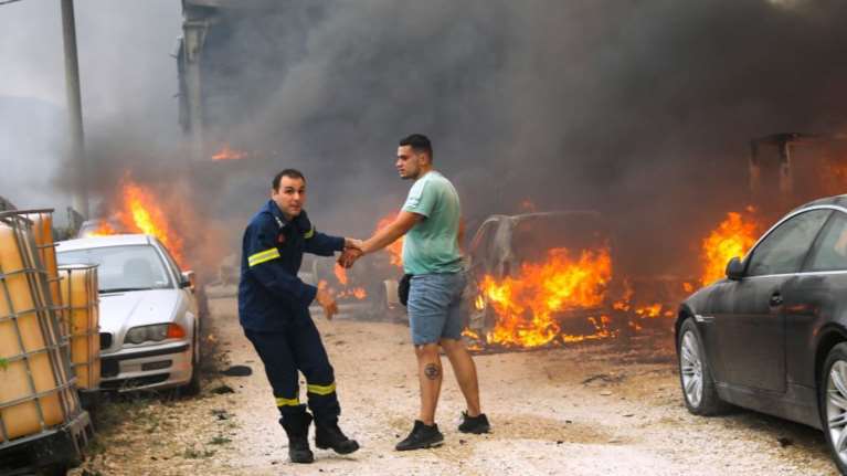 Φωτιά στην Αττική: &quot;Καρέ - καρέ&quot; ο αγώνας πυροσβέστη να απομακρύνει ιδιοκτήτη μάνδρας αυτοκινήτων που καίγεται