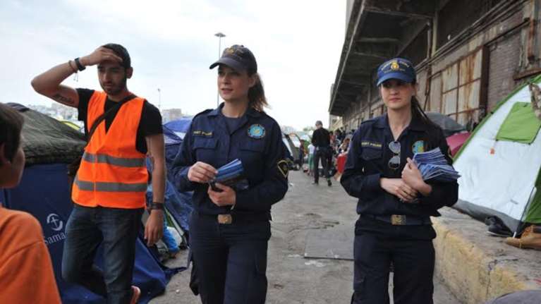 Γυναίκες λιμενικοί μοιράζουν το φυλλάδιο στους πρόσφυγες στο Λιμάνι