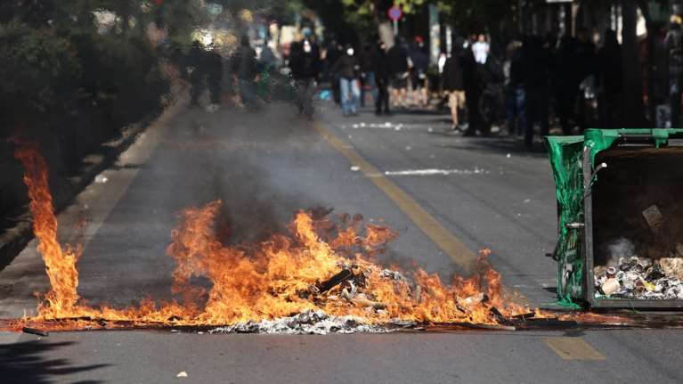 Επεισόδια έξω από την ΑΣΟΕΕ: Έβαλαν φωτιά σε κάδους και έσπασαν τζαμαρία τράπεζας