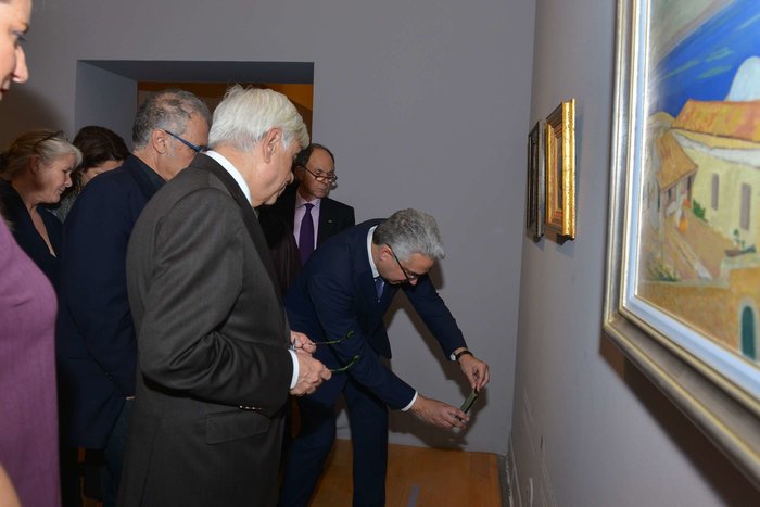 Ο διευθυντής του Κέντρου Έρευνας και Τεκμηρίωσης της Τράπεζας της Ελλάδος Παναγιώτης Παναγάκης δείχνει στον Πρόεδρο της Δημοκρατίας την εφαρμογή audio guide, μέσω της οποίας ο επισκέπτης της έκθεσης παίρνει πληροφορίες για τα έργα μέσα από το κινητό του.
